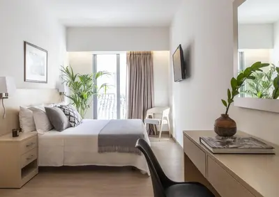 a bedroom with a bed and a desk with a chair at Gallery Suites & Residences Piraeus in Piraeus