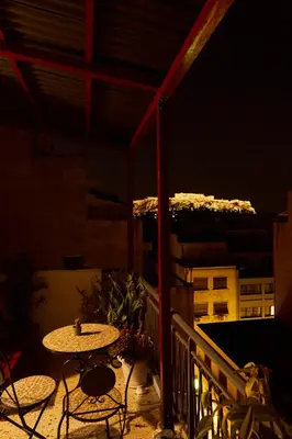 a table and chairs on a balcony at night at Mosaics Athens Penthouse with Acropolis view in Athens