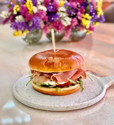 a sandwich on a plate on a table with flowers at Athens Ivy Suites in Athens
