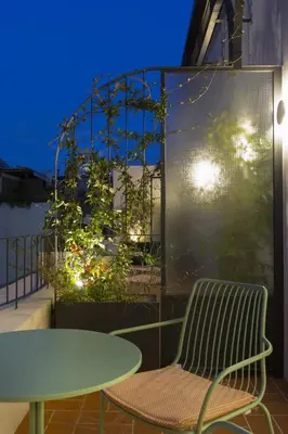 a table and a bench on a balcony at night at L'Avventura Athens in Athens