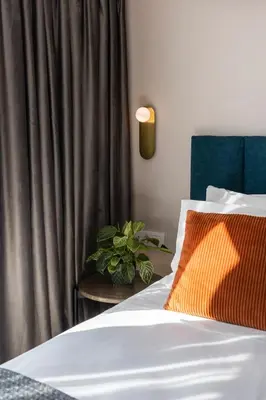 a bed with an orange pillow next to a curtain at L'Avventura Athens in Athens