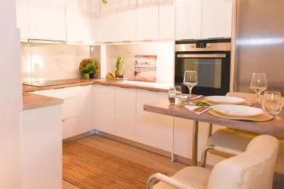 a kitchen with white cabinets and a table with wine glasses at Acropolis Sweet House 2 in Athens