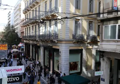 a crowd of people walking down a street in front of a building at Syntagma Sweet House in Athens