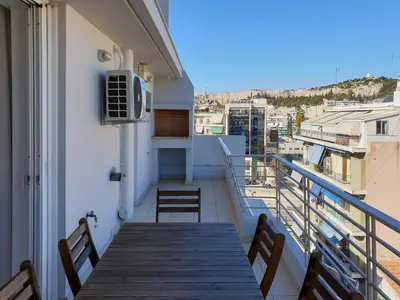 a balcony with a wooden table and chairs at KYMA Apartments - Athens Acropolis 15 in Athens