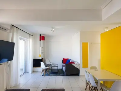 a living room with a table and a yellow wall at KYMA Apartments - Athens Acropolis 15 in Athens