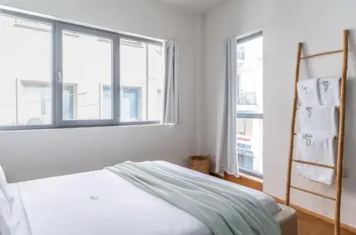 a white bedroom with a bed and two windows at LOFUS Bio-Suites in Athens