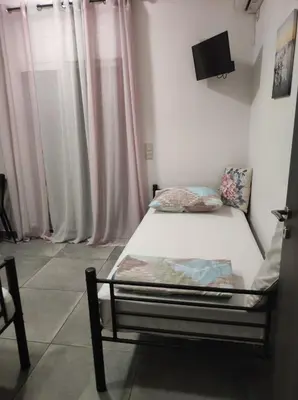 a bed in a room with curtains and a tv at PHOENIX apartment near the airport in Markopoulo