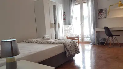 a bedroom with a bed in a room with windows at Petrol Apartment- Athens Center, 4 BD, 1 BATH in Athens