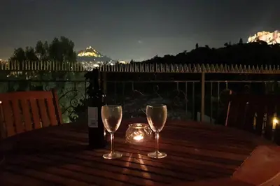 a table with two glasses and a bottle of wine at Ground floor apt with rooftop and stunning view in Athens