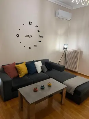 a living room with a couch and a clock on the wall at Alimos Cozy Getaway, close to the beach in Athens