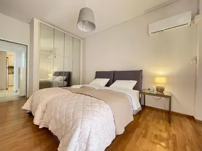 a bedroom with a large bed with a white blanket at Cassiopeia - Glyfada Apartment in Athens