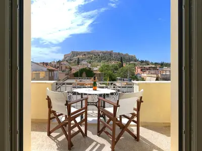 a table and chairs on a balcony with a view at The Prestige Acropolis Penthouse in Athens