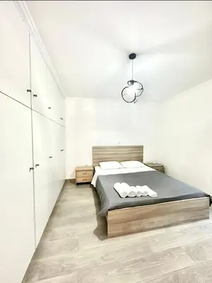a white bedroom with a bed and a chandelier at The Aegean Nest in Athens