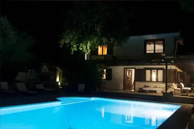 a swimming pool in front of a house at night at villa eleni in Sounio