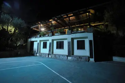 a building with a tennis court at night at villa eleni in Sounio