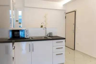 a white kitchen with a sink and a microwave at Koukaki lux 2BD 1master ap next to Acropolis in Athens
