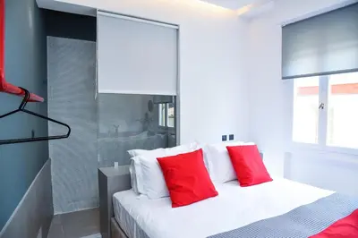 a white bed with red pillows in a room at CentraL44 LoL RooM-Ermou Street in Athens