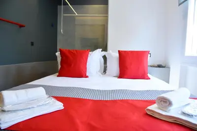 a bed with red and white pillows and towels on it at CentraL44 LoL RooM-Ermou Street in Athens