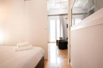 a bedroom with a white bed and a hallway at Hidden Gem Acropolis View in Athens