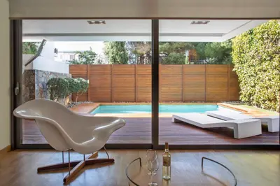 a living room with a white chair and a swimming pool at Elegant and Private Living by Neuvel in Athens