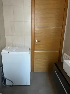 a bathroom with a refrigerator and a wooden door at ΔΙΑΜΕΡΙΣΜΑ ΜΕ ΘΕΑ in Athens