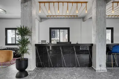a lobby with a black counter and potted plants at Play Theatrou Athens a member of Brown Hotels in Athens