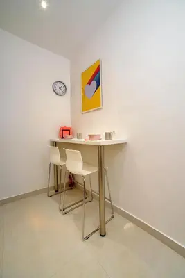 a table and chairs in a room with a clock at Acropolis area family friendly 2bdr apartment in Athens