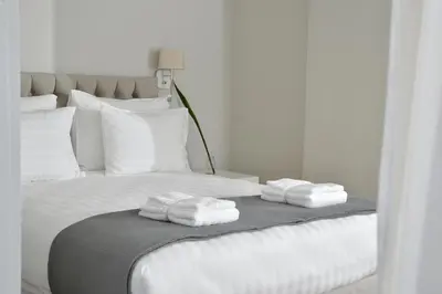 a white bed with two folded towels on it at 1900 ATHENIAN HOUSE in Athens
