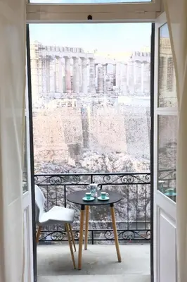 a balcony with a table and a view of the coliseum at 1900 ATHENIAN HOUSE in Athens