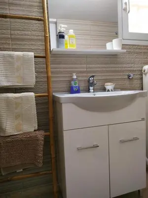 a bathroom with a sink and a shelf with towels at Emily`s vacation house in Kalívia Thorikoú