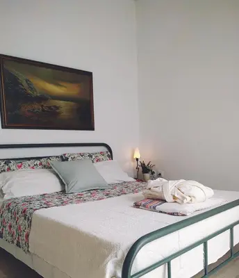 a bedroom with a bed with a painting on the wall at Emily`s vacation house in Kalívia Thorikoú