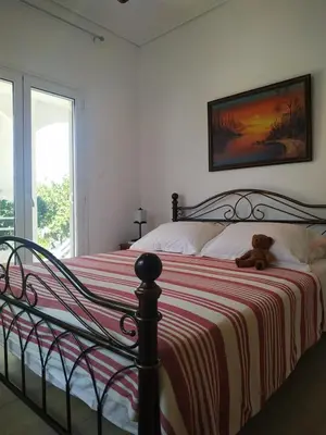 a teddy bear sitting on a bed in a bedroom at Emily`s vacation house in Kalívia Thorikoú