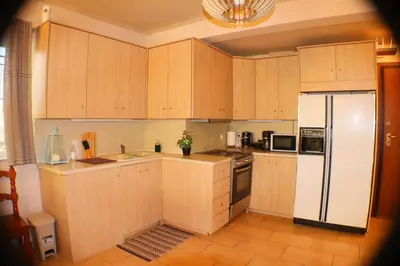 a kitchen with wooden cabinets and a white refrigerator at Filoxenia Apartment in Athens