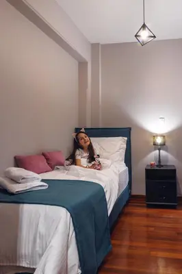 a little girl laying on a bed in a bedroom at Athens Chic House in Athens