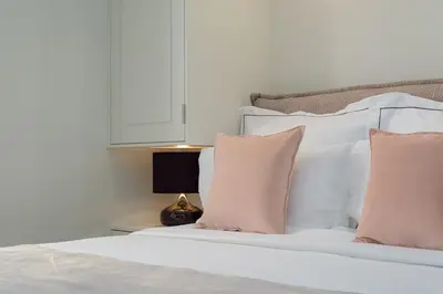 a bedroom with a bed with white sheets and pink pillows at THIRAMENOUS RESIDENCE in Athens