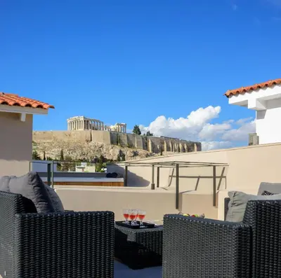 a patio with wicker chairs and wine glasses on a roof at THIRAMENOUS RESIDENCE in Athens