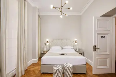 a white bedroom with a bed and a chandelier at MiraMe Athens Boutique Hotel in Athens