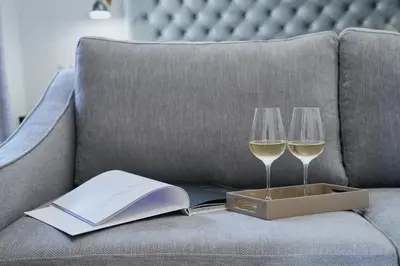 two glasses of white wine and a book on a couch at MiraMe Athens Boutique Hotel in Athens