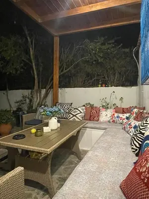 a patio with a table and a couch with pillows at Lagonisi MAGIC HOME RELAXATION in Kalívia Thorikoú