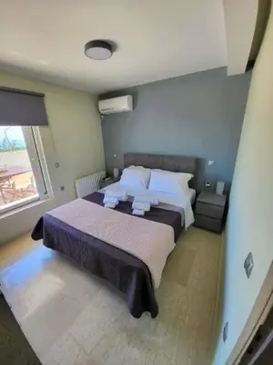 a bedroom with a large bed and a window at ''Stergiou Luxury Apartments'' με κοινη πισινα in Saronida