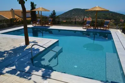 a large swimming pool with chairs and umbrellas at ''Stergiou Luxury Apartments'' με κοινη πισινα in Saronida