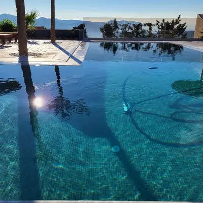 a swimming pool with blue water and palm trees at ''Stergiou Luxury Apartments'' με κοινη πισινα in Saronida
