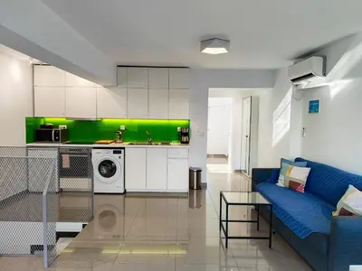 a living room with a blue couch and a green kitchen at KYMA Apartments Athens 19 in Athens
