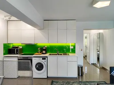 a kitchen with white cabinets and a green wall at KYMA Apartments Athens 19 in Athens