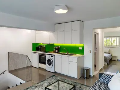 a kitchen with white cabinets and a green wall at KYMA Apartments Athens 19 in Athens