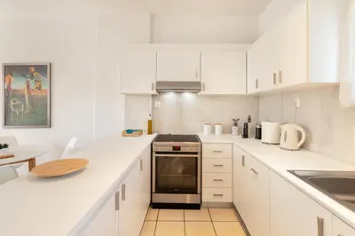 a kitchen with white cabinets and a stove top oven at Del Mar Luxury Apartment 30m From The Beach in Porto Rafti