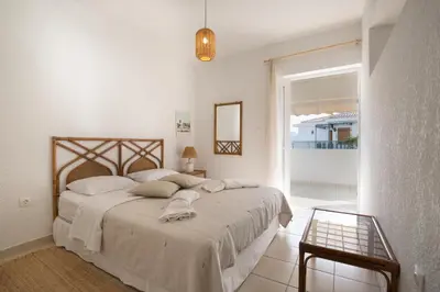 a white bedroom with a large bed and a window at Del Mar Luxury Apartment 30m From The Beach in Porto Rafti