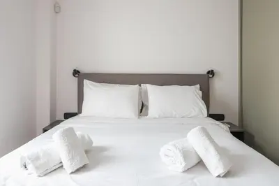 a white bed with three white towels on it at Petraki Residence 1bdr Apt with balcony 1 min from Ermou str in Athens