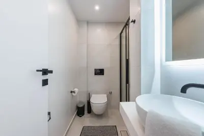 a white bathroom with a toilet and a sink at Petraki Residence 1bdr Apt with balcony 1 min from Ermou str in Athens