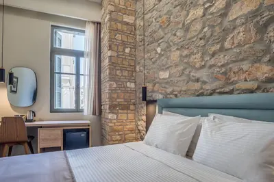a bedroom with a bed and a stone wall at Philia Boutique Hotel in Athens